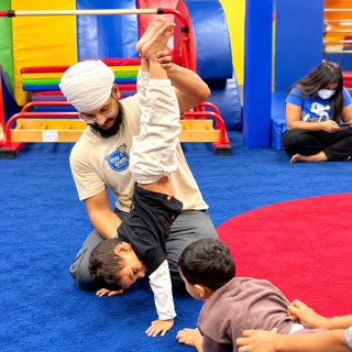 Coach guiding a child through a stretch at My Gym Ludhiana